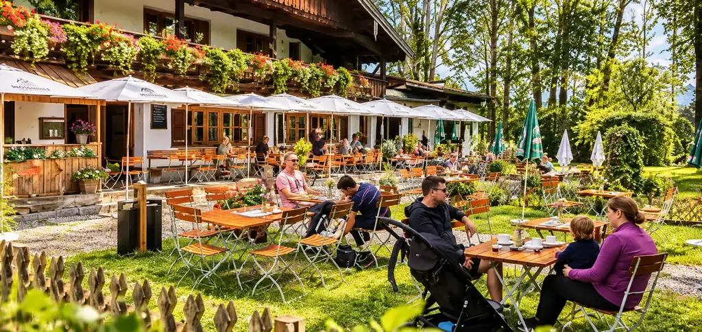 Gäste an Holztischen im sonnigen Naturgarten vor der blumengeschmückten Moosmühle