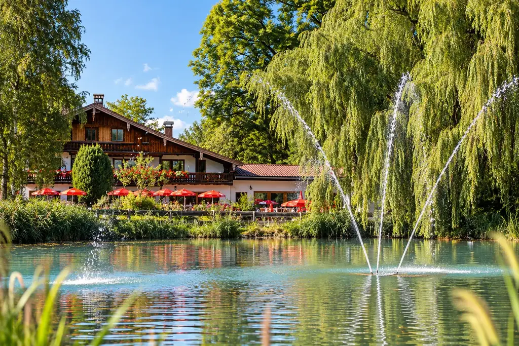 Teich mit Fontäne vor der Moosmühle, gesäumt von Trauerweiden und Schilf
